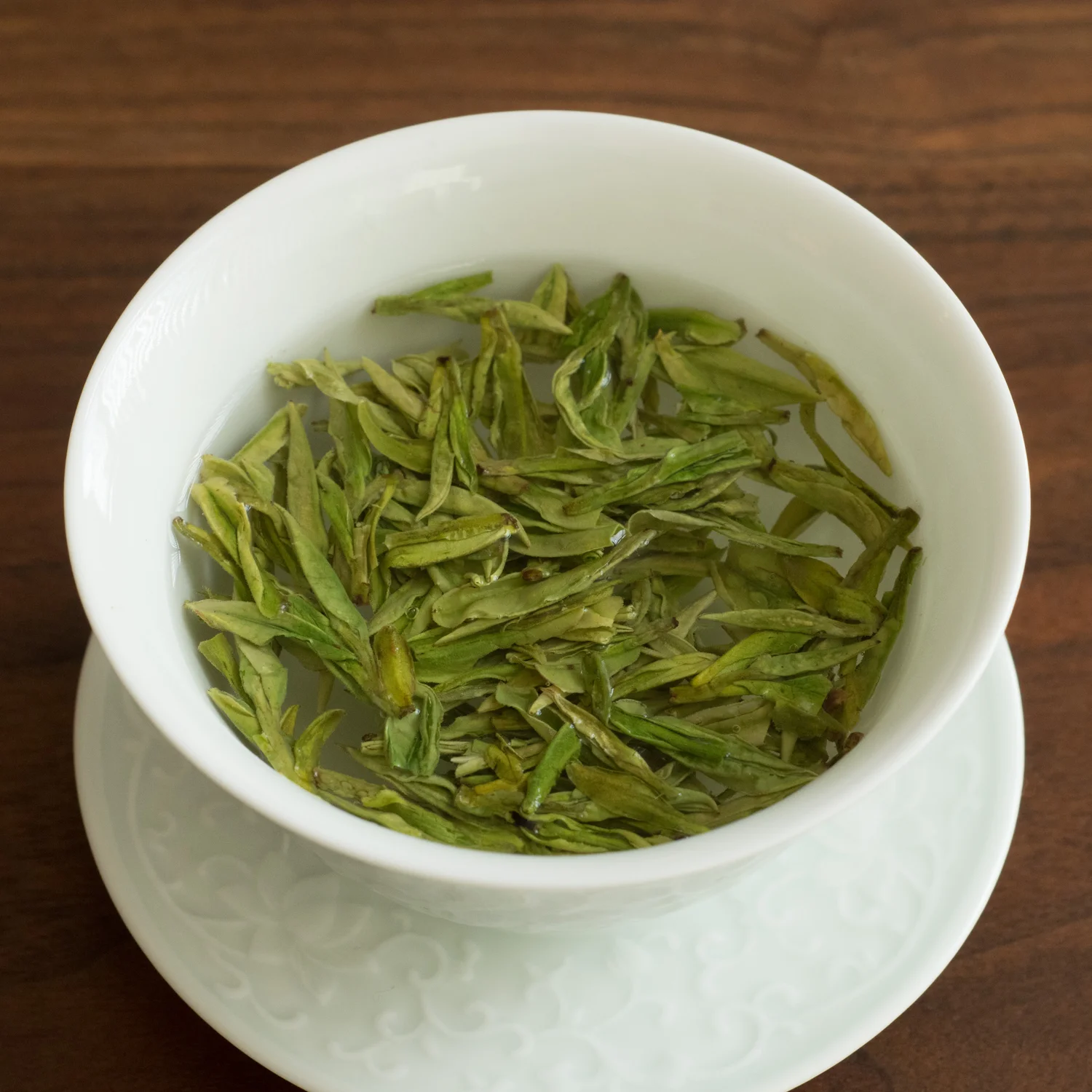 白瓷盖碗里舒展的龙井茶叶